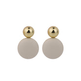 Gold and white round drop earrings made of man-made leather, beautifully emphasizing their chic appeal.